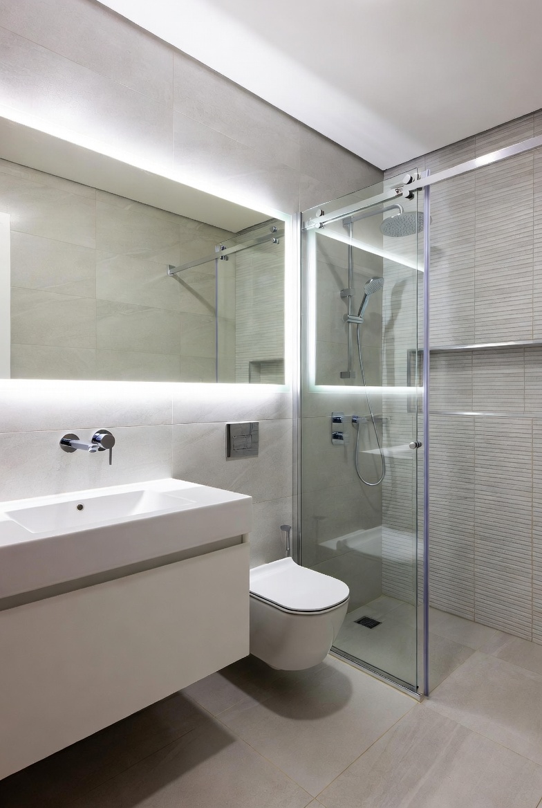 A beautifully designed small modern bathroom with floating vanity, frameless glass shower, large-format tiles, backlit mirror, and wall-hung toilet, showcasing smart space-saving luxury interior design ideas for tiny bathrooms.